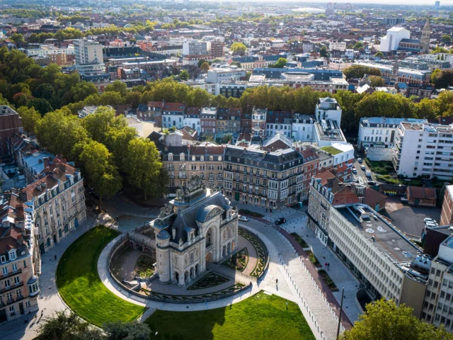 Vue aérienne de la Porte de Paris à Lille, entourée de bâtiments haussmanniens et d’espaces verts, prise depuis le beffroi de l’Hôtel de Ville.