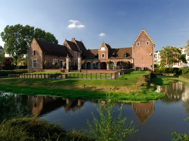 Château de Flers à Villeneuve-d’Ascq, bâtiment en briques rouges bordé de douves et de pelouses verdoyantes.