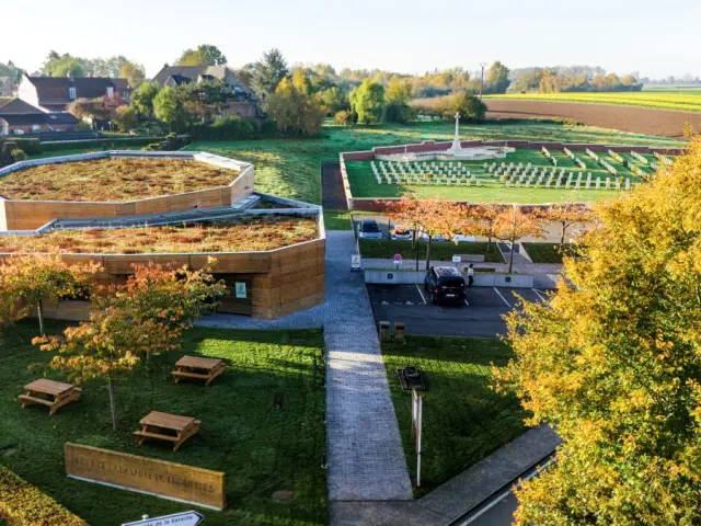 Vue aérienne du Musée de la Bataille de Fromelles et du cimetière militaire adjacent, entourés de maisons et de champs verdoyants.