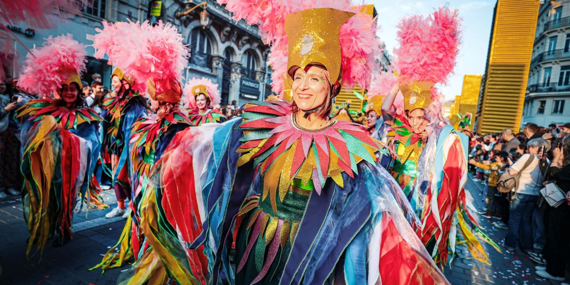 Danseuses en costumes multicolores et coiffes à plumes roses défilant lors de la 7ᵉ édition de la parade Fiesta lille3000.